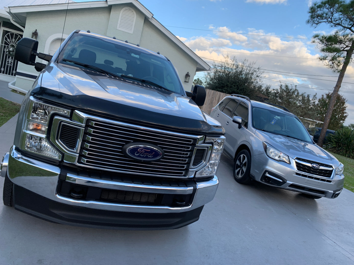 A Ford Super Duty and Subaru Outback, both detailed to perfection, parked together showing off their clean and shiny exteriors, reflecting the care and attention given to both vehicles by Finishline Detailing Garage.