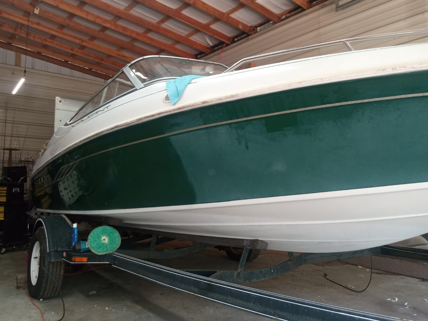 Half-and-half image of a green boat, showcasing the difference before and after paint correction, with one side restored to a smooth, glossy finish.