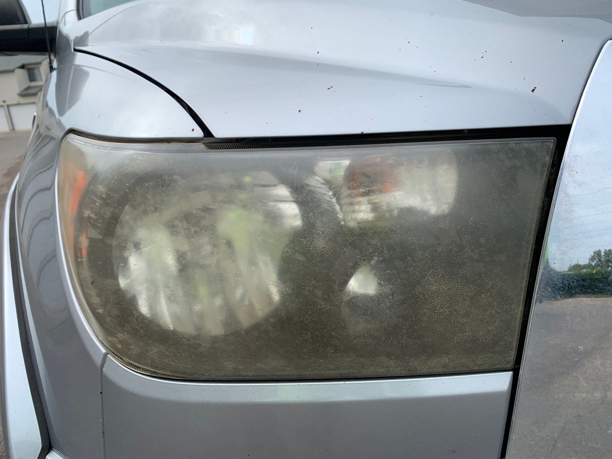 Headlight before restoration treatment showing yellowing and oxidation.
