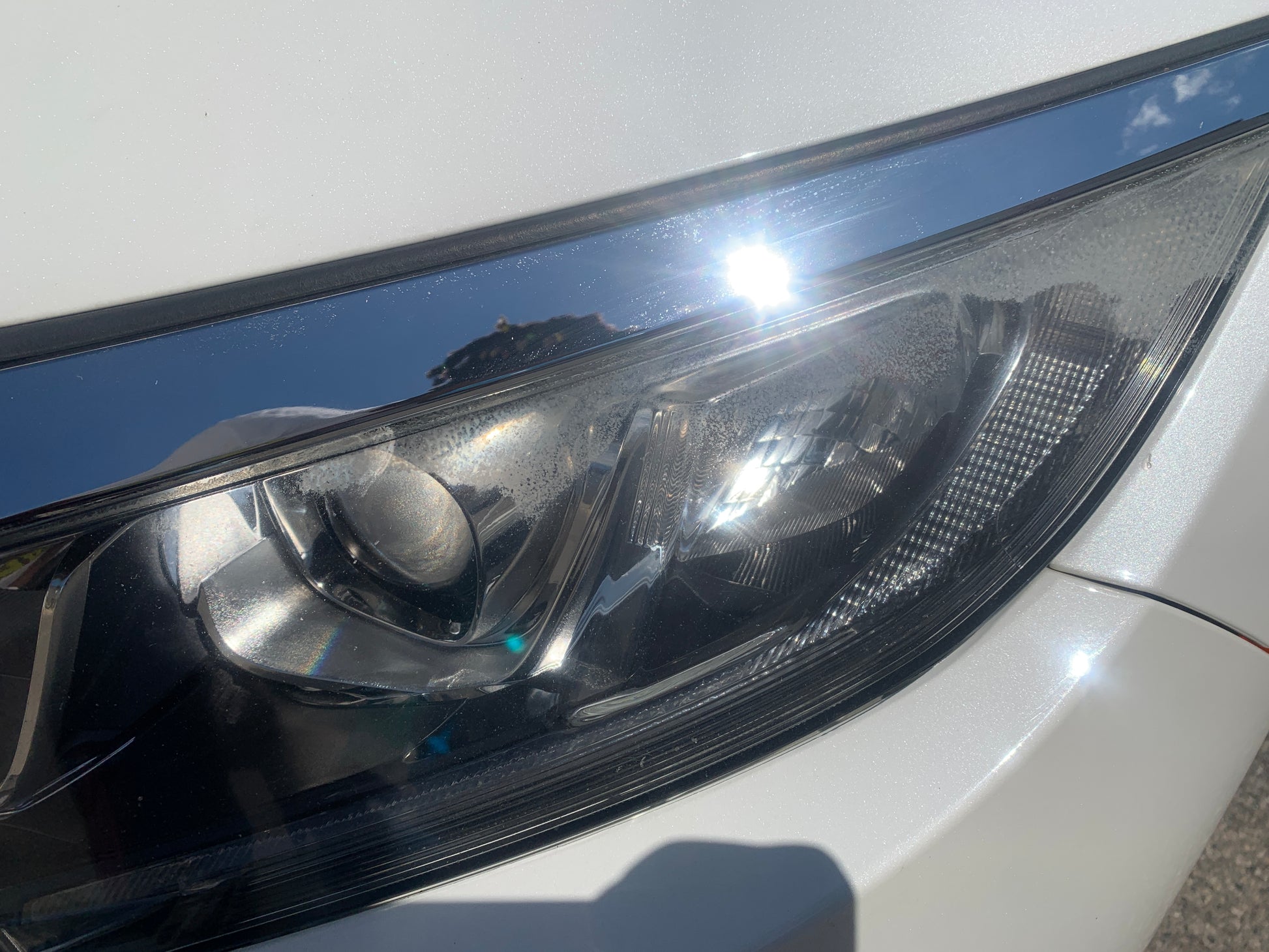 Restored headlight shining brightly in the sun after a thorough restoration, showcasing improved clarity and shine.