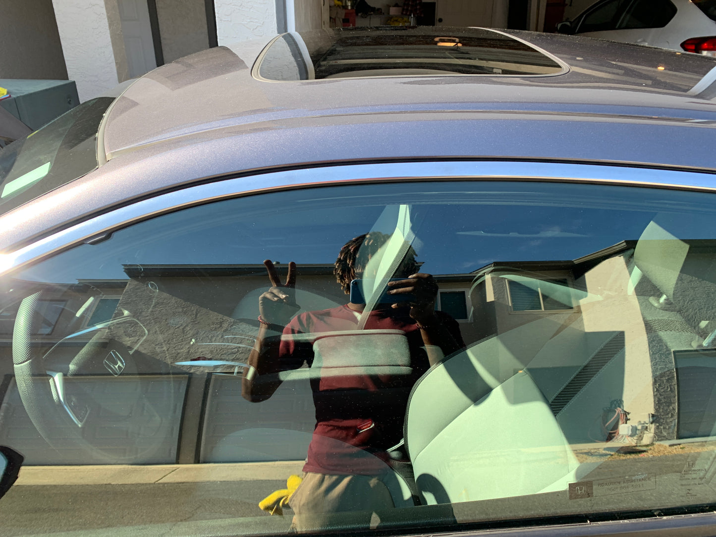 Reflection of the detailer in the window, making the peace sign, capturing a fun moment during the detailing process.