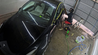 Bird’s eye view of me applying wax to the Tesla, showcasing the detailed process and focus on achieving a smooth, glossy finish.