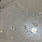 Detailed view of water beading on pearl white car paint after ceramic coating application.