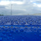 Macro shot of water beading on a blue vehicle surface treated with graphene ceramic coating.