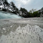 Close-up view of water beads forming on a vehicle’s surface outdoors, showcasing ceramic coating’s protection.