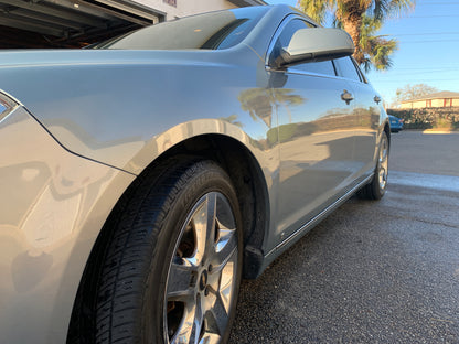 Low angle shot of the side of a vehicle showing reflections of bushes and trees on the shiny surface after detailing.