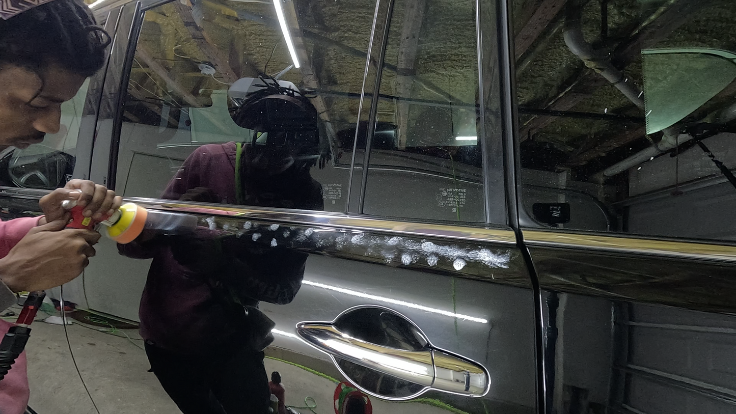 Close-up of a technician using a mini polisher to work on the detailed edges of a car door, removing defects and leaving a smooth, flawless finish.
