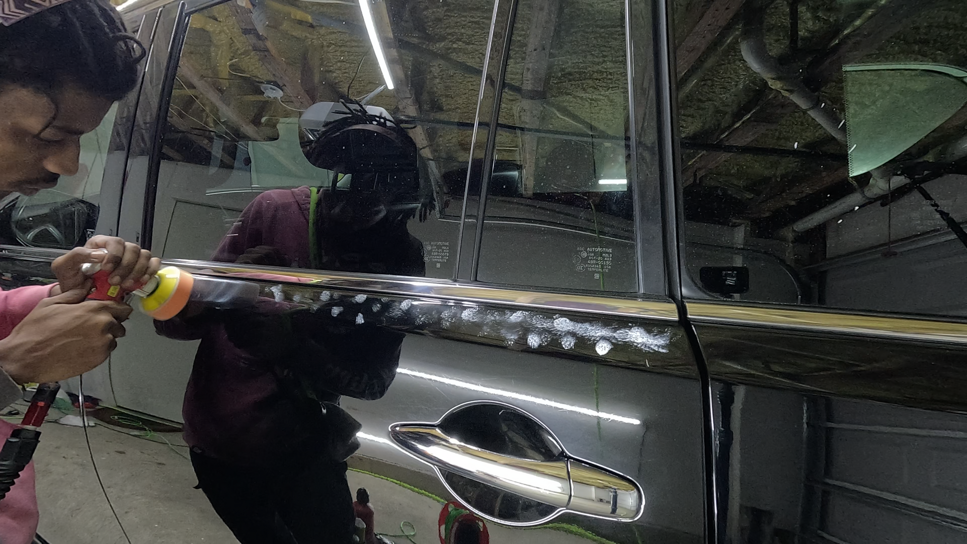 Close-up of a technician using a mini polisher to work on the detailed edges of a car door, removing defects and leaving a smooth, flawless finish.