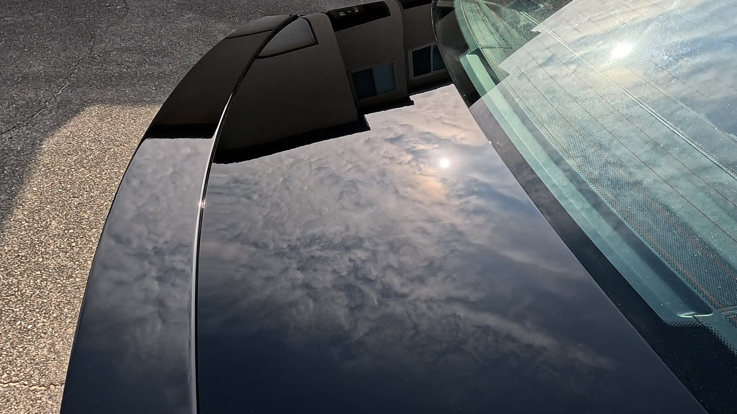 The trunk of a limited edition Mercedes reflecting the clouds and sun, showcasing the glossy finish after paint correction and ceramic coating.
